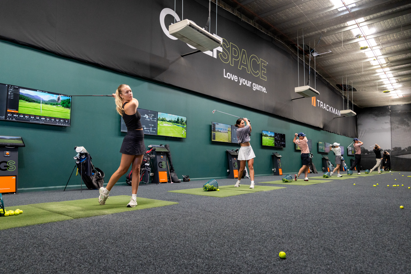 Golfers practising on the indoor TrackMan driving range