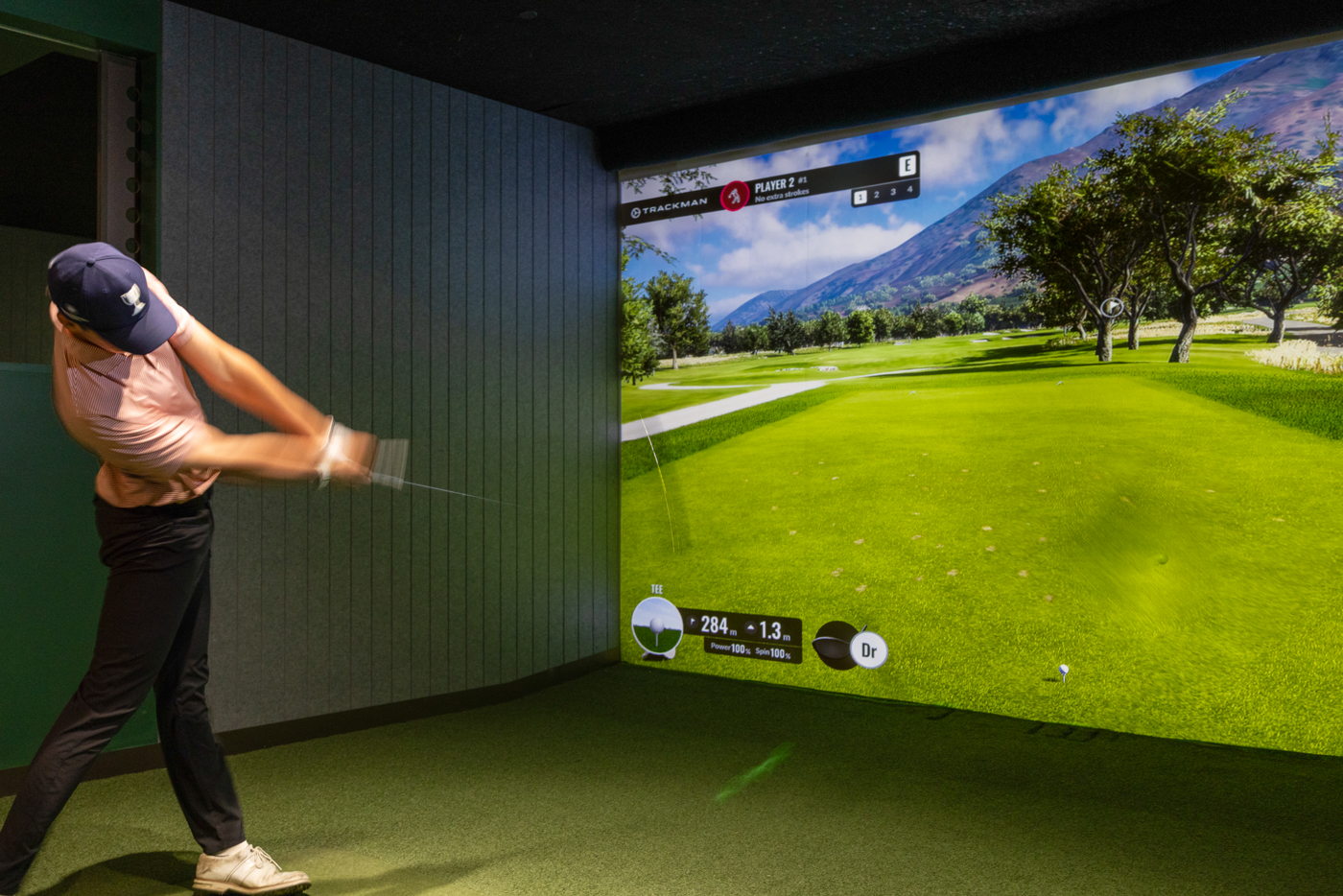 A golfer playing in a GolfSpace TrackMan simulator bay