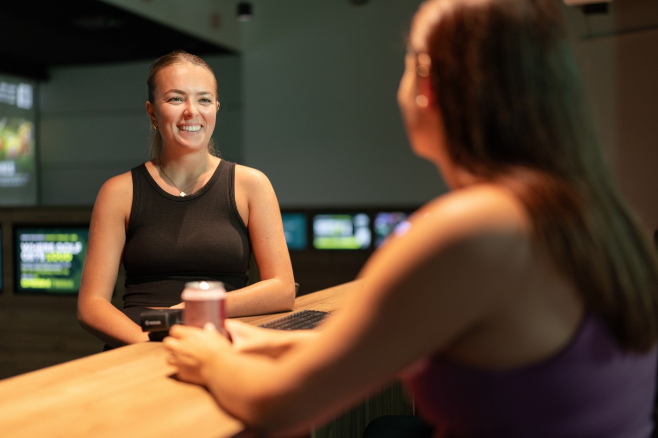 Issi welcoming a woman at the GolfSpace bar